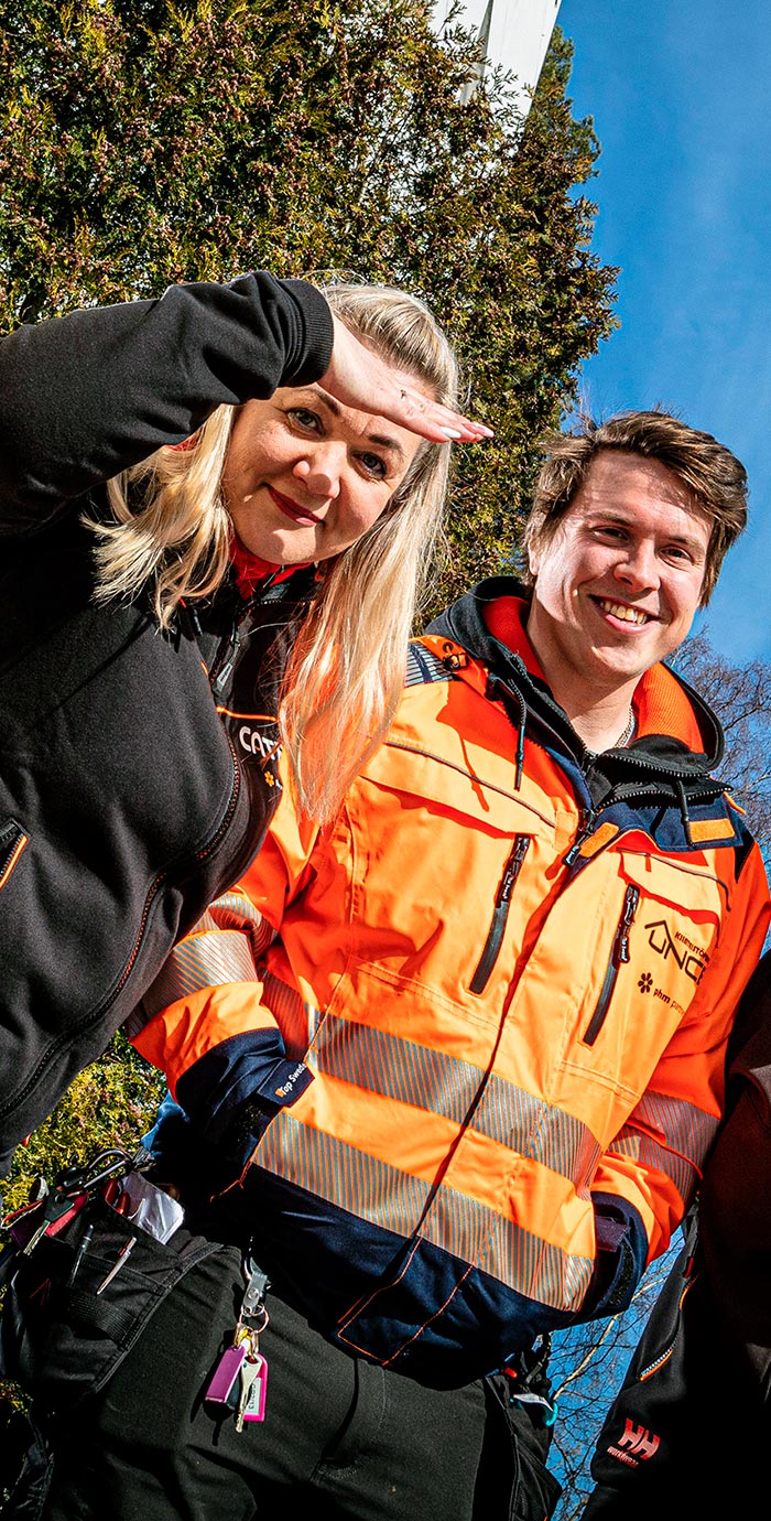 Two women and a man smile at the camera in front of a van